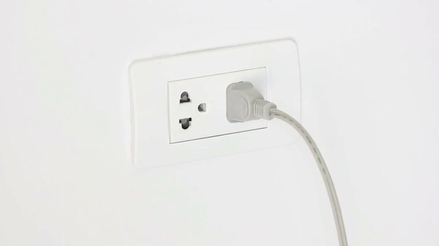 Close Up Of A Hand Plugging In A Power Cord And Then Unplugging It In A Typical Electrical Outlet.