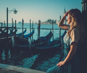 Beautiful well-dressed woman standing near San Marco square with gondolas and Santa Lucia island on the background.  © Nejron Photo