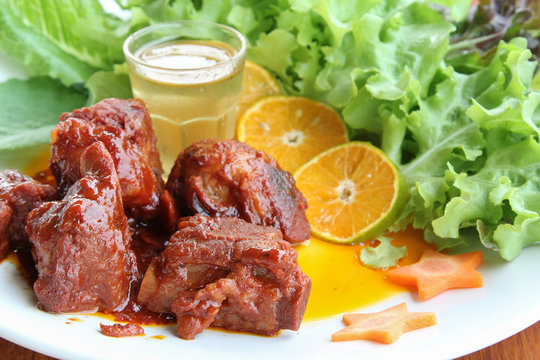 Chinese sweet and sour pork ribs on white plate.