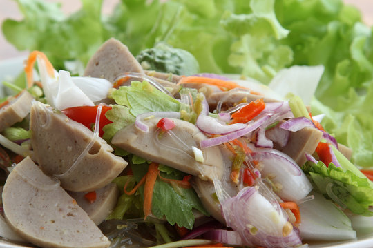 Thai cuisine spicy pork salad on white plate.