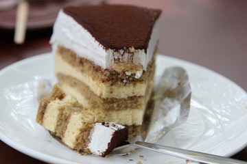 Slice of dessert tiramisu cake topping with cocoa powder on the plate.