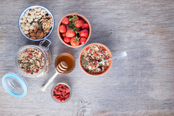 Grain free oat free paleo muesli, raw food: mixed nuts, seeds, goji berries, chia, honey and strawberries, selective focus