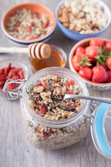 Grain free oat free paleo muesli, raw food: mixed nuts, seeds, goji berries, chia, honey and strawberries, selective focus