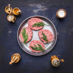 raw homemade burgers Beef, lined inside vintage pan with spices and herbs on a blue rustic wooden background top view