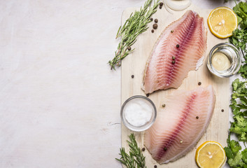raw fillet of tilapia with salt, lemon and butter, rosemary and herbs, border  place for text