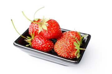 Garden strawberry in black vase isolated on white background