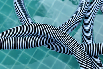 Closeup swimming pool vacuum hose floating on water