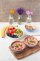 Vegan fruit and berry smoothie breakfast, topped with blueberries, strawberries and mint, seved with fruits, berries and nuts, selective focus