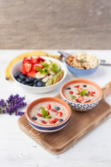 Vegan fruit and berry smoothie breakfast, topped with blueberries, strawberries and mint, seved with fruits, berries and nuts, selective focus