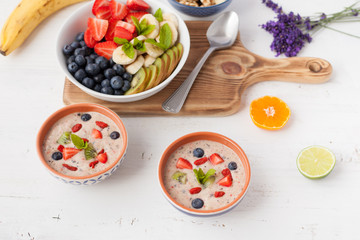 Vegan fruit and berry smoothie breakfast, topped with blueberries, strawberries and mint, seved with fruits, berries and nuts, selective focus