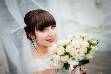 Naklejka premium Beautiful smiling bride portrait near architecture with flowers