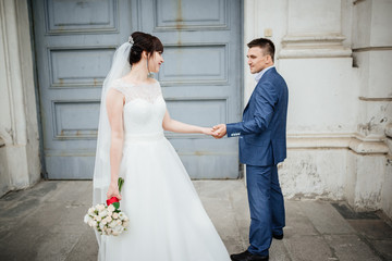 Fototapeta premium Bride and groom at wedding Day walking Outdoors near architecture. Bridal couple, Newlywed woman and man embracing with love