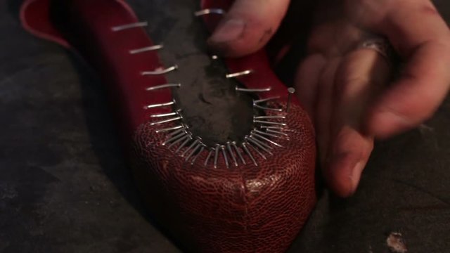 Shoemaker sews shoes. Hammering shoe leather