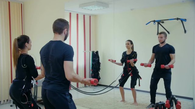 Male fitness instructor works with woman wearing ems