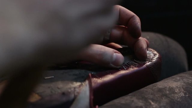 Shoemaker sews shoes. Hammering shoe leather
