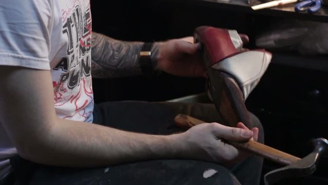 Shoemaker sews shoes. Hammering shoe leather