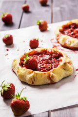 Rustic Tarts with strawberries on a white paper for baking 