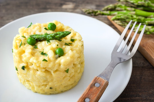 Risotto with asparagus, parsley and peas on a rustic wooden table

