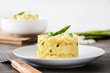 Risotto with asparagus, parsley and peas on a rustic wooden table

