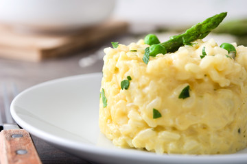 Risotto with asparagus, parsley and peas on a rustic wooden table

