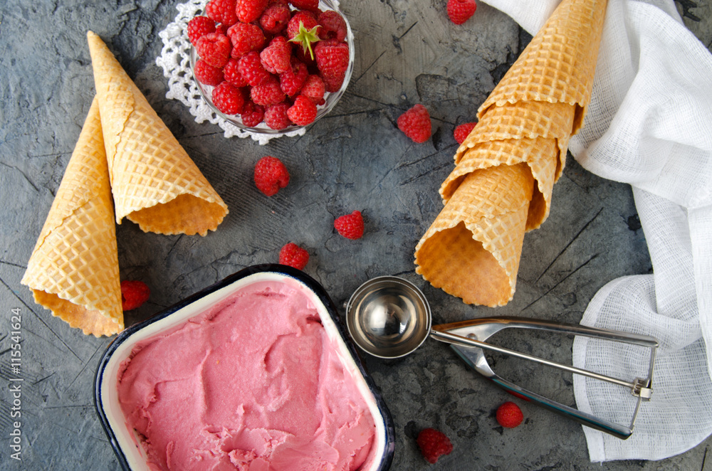 Fototapete Raspberry ice cream with ice cream cones on stone table. Top view.