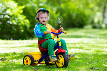Little boy on colorful tricycle - obrazy, fototapety, plakaty