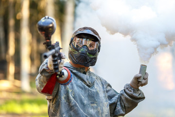 Obraz premium Cool guy with paintball gun and smoke grenade