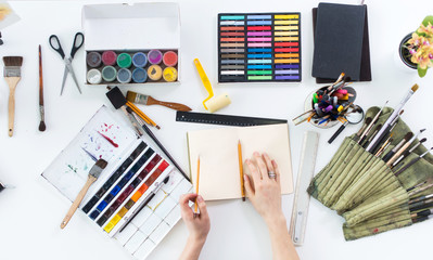 Artist drawing graphic sketch at sketchbook. Workplace, workspace. Top view photo of artistic tools...