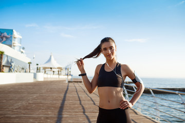 Picture of young fitness girl ready for sport exercises with sea coast on background