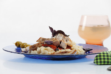 Traditional italian risotto with chicken, tomato, basil and parmesan on blue plate with knife and fork and glass of wine