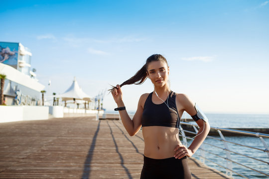 Picture of young fitness girl ready for sport exercises with sea coast on background