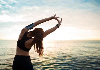 Picture of young beautiful fitness girl makes sport exercises with sea on background