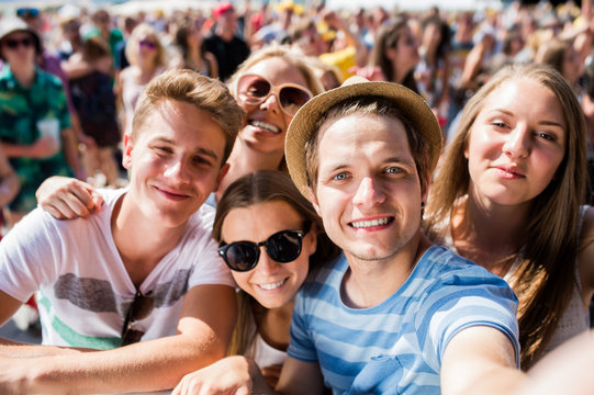 Teenagers at summer music festival in crowd taking selfie