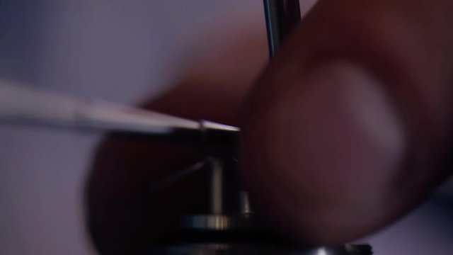 Installing winding on base of clearomizer, using coil jig, tightening of screws closeup.