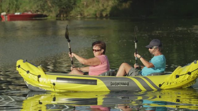 SLOW MOTION: Happy mature couple kayaking on the lake