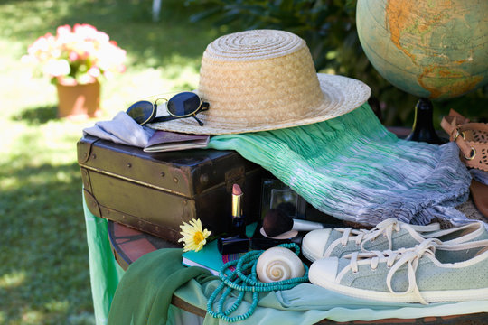 Travel preparations on a table, retro suitcase with women summer outfit