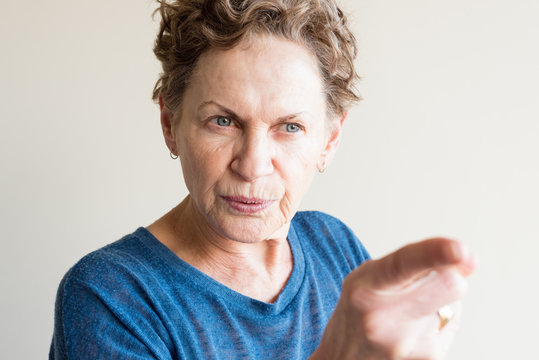 Angry older woman in blue top pointing finger (selective focus)
