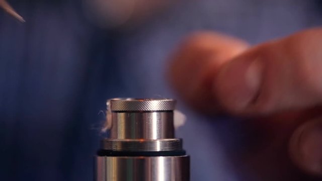 Compaction wick of cotton wool at electronic cigarette and tightening cap, closeup.