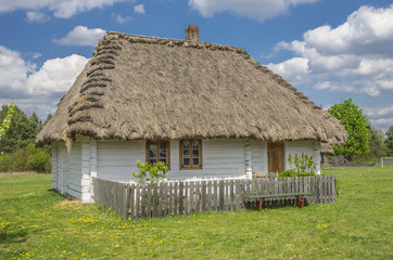 Fototapeta na wymiar wiejski mały, biały domek pokryty strzechą z ogródkiem