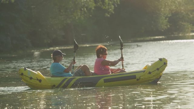 SLOW MOTION CLOSEUP: Mature couple kayaking at summer sunset