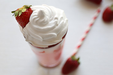 Delicious strawberry milkshake on wooden table