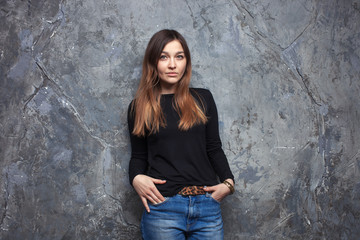 Bright fashion portrait of pretty brunette woman wearing casual outfit posing on urban grey textured background