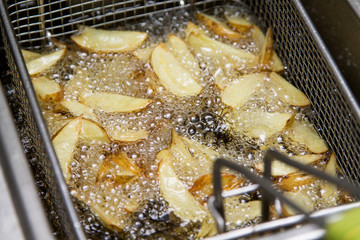 Fastfood kitchen - potatoes frying  in the oil in the fritter
