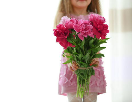 Girl holding fresh peonies bouquet on curtains background