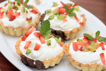 Tarts with whipped cream and strawberries and mint leaves
