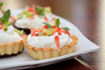 Tarts with whipped cream and strawberries and mint leaves