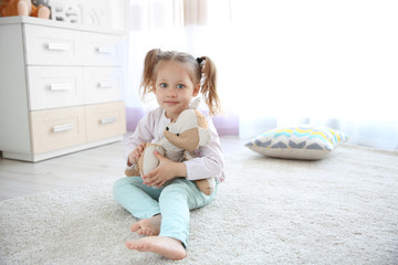 Small cute girl with teddy bear at home