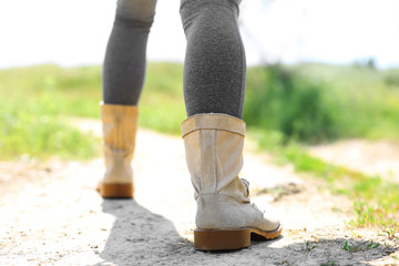 Back view of female hiker legs with boots going up the hill at sunny day