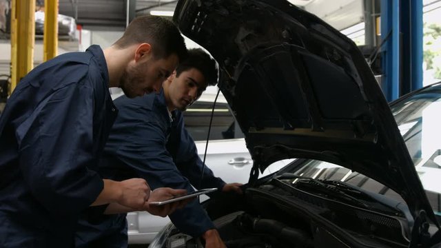 Handsome mechanics overhauling a car in the garage
