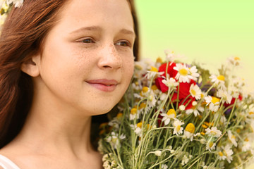 Portrait of girl in meadow with wild spring flowers bouquet